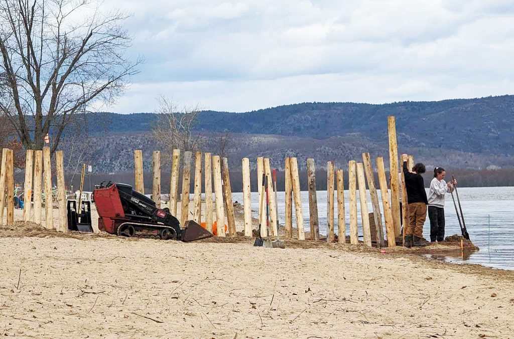 People erect a fence on the beach.