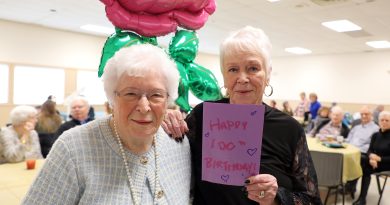 A mom and daughter pose for a photo with a birthday card.