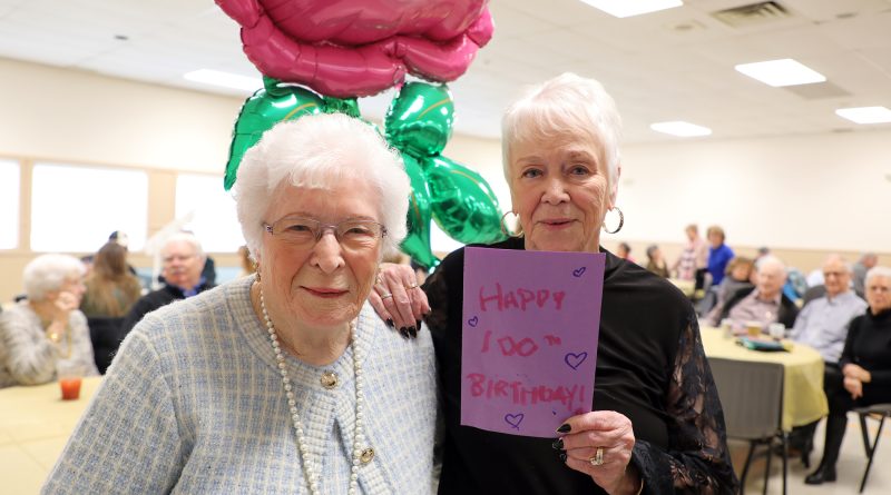 A mom and daughter pose for a photo with a birthday card.