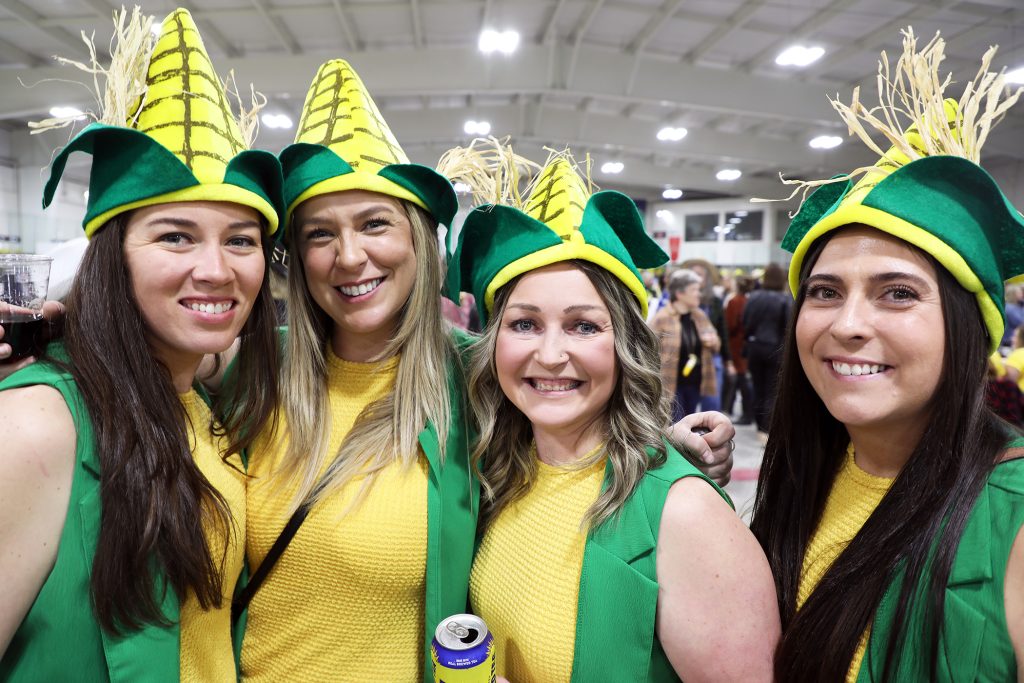 Four women dressed as corn pose for a photo.