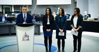 Four people stand at a podium at city hall.