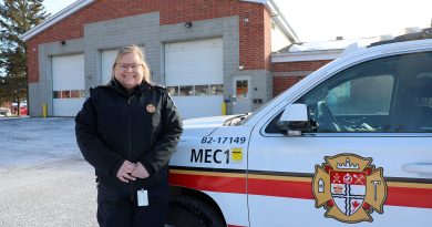 A fire prevention officer poses in front of a fire hall.