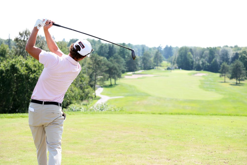 A man tees off at a golf course.