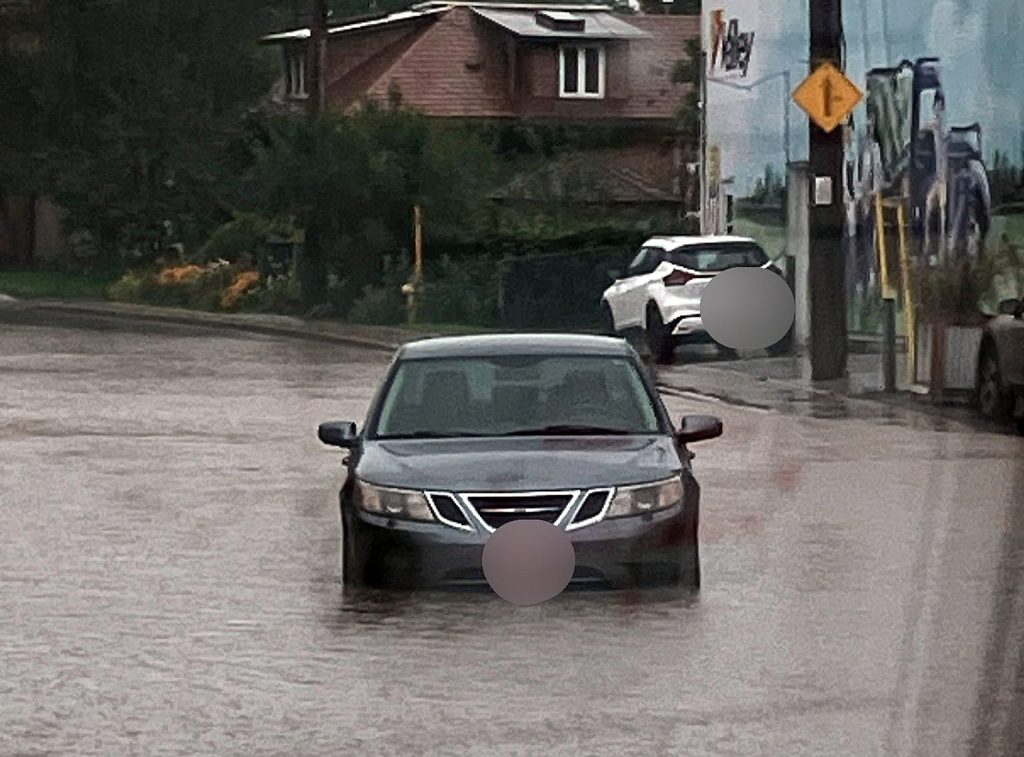 A car travels down a flooded road.