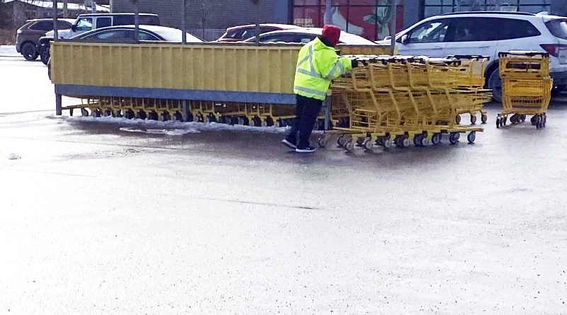 An employee pushes shopping carts.