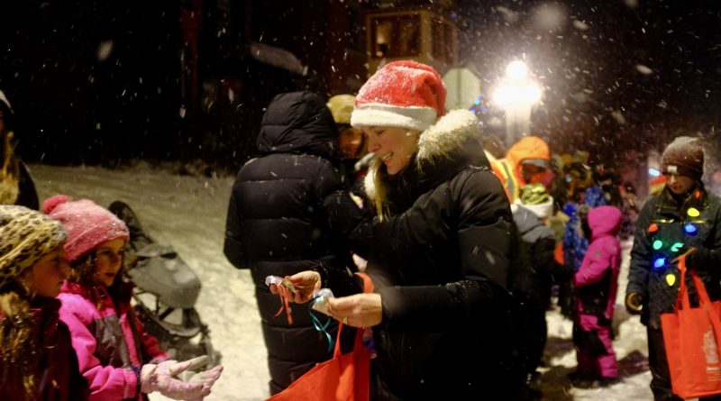 A woman hands out candy during a parade.