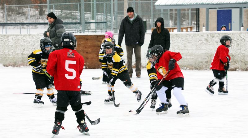 Kids play hockey outdoors.