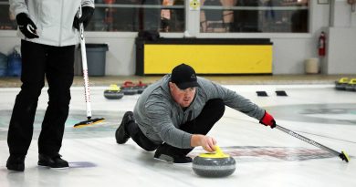 A man delivers a stone during a curling match.