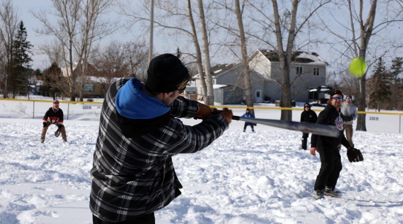 A player takes a swing during a snow pitch tournament.