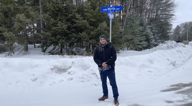 A man stands by a street sign.