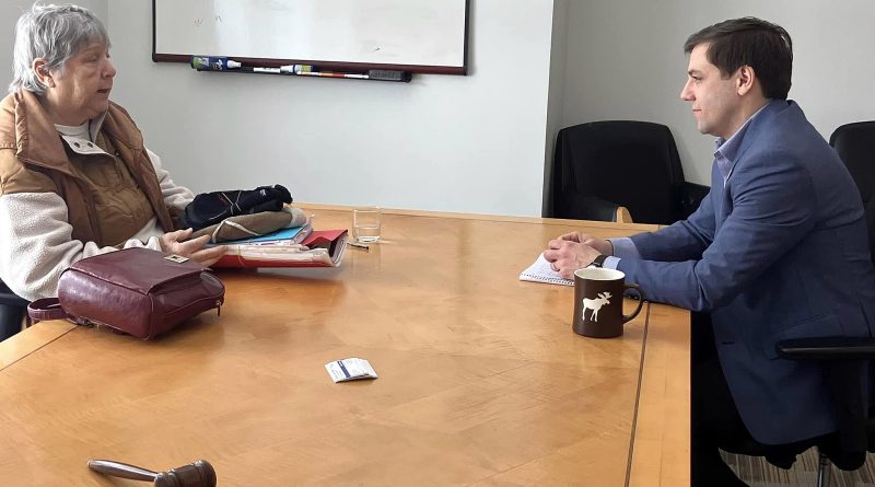 Two people talk at a table.