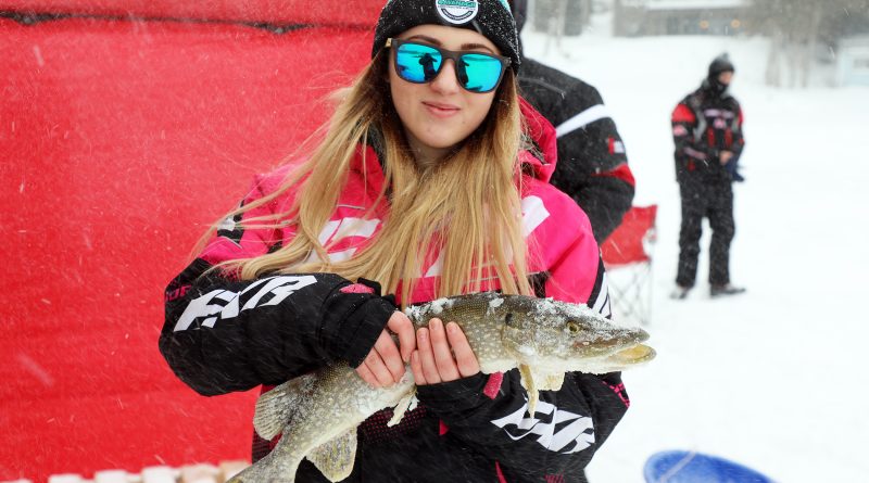 A young woman holds a big fish.