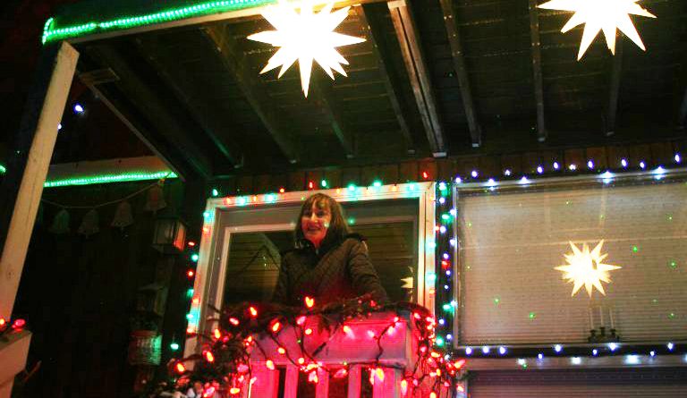 A woman poses amidst Christmas lights.