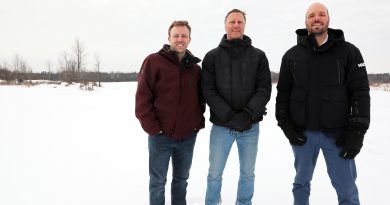 Three people pose in a snowy field.