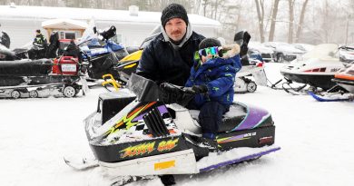 A dad and son pose by a tiny sled.