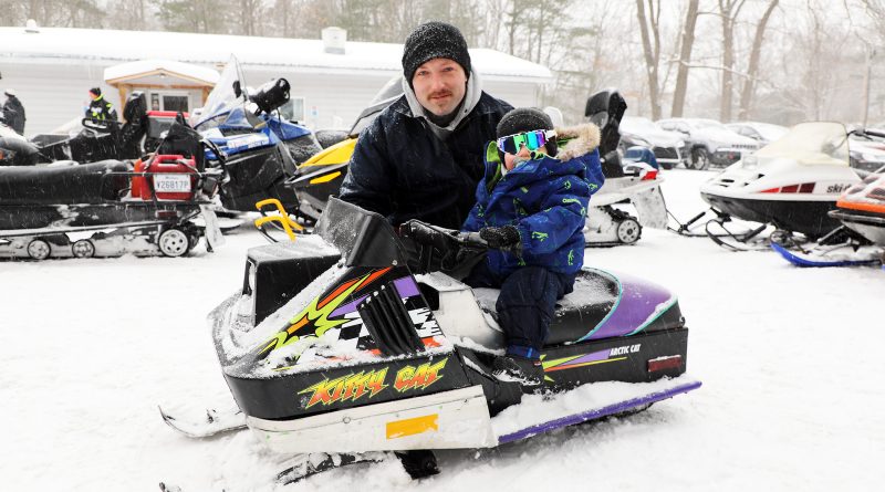 A dad and son pose by a tiny sled.