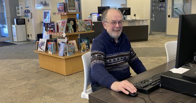 A man works at a computer in a library.