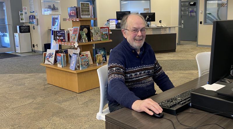 A man works at a computer in a library.