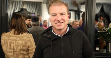 A man poses in a busy bar.