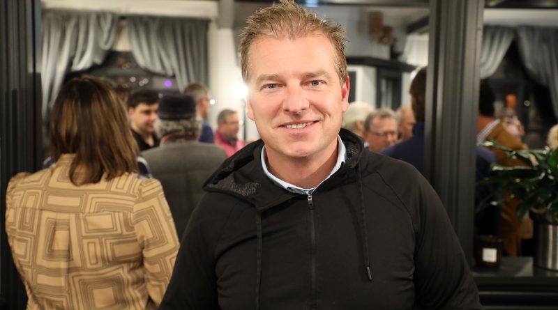 A man poses in a busy bar.