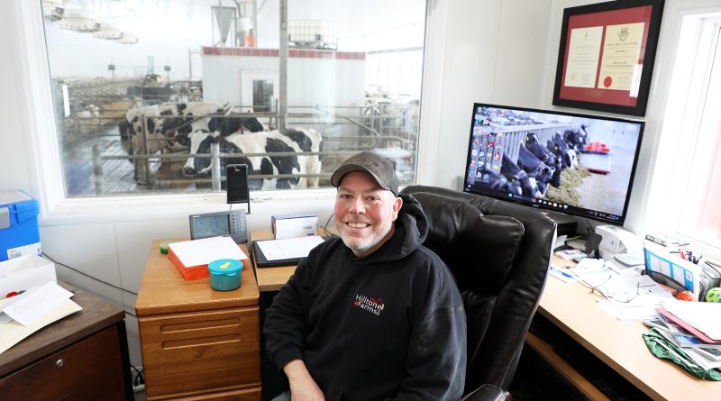 A farmer sits in his office overlooking his dairy herd.