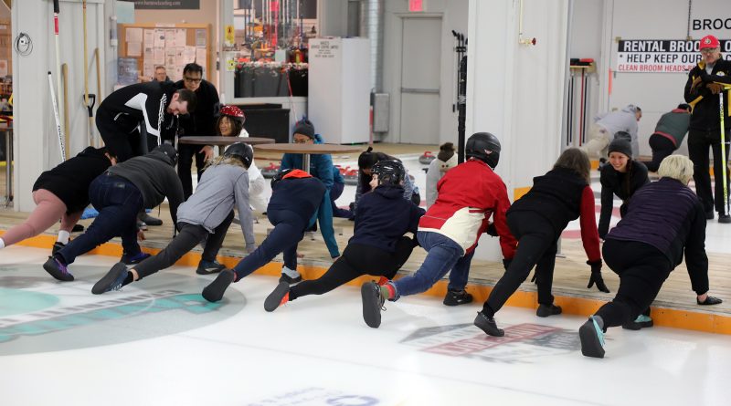 People stretch on a curling rink.
