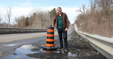 A man stands by a pothole.