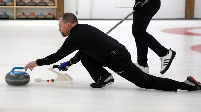 A man throws a curling stone.