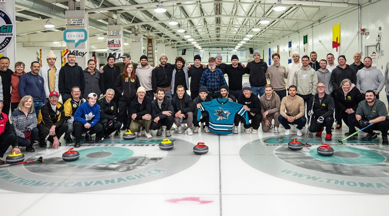 A large group of hockey players and curlers pose for a photo.