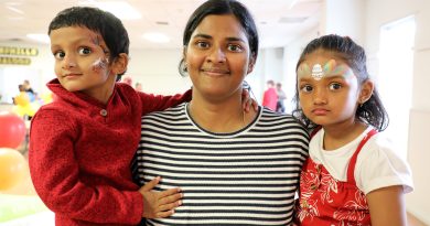 Three people, two with face paint, pose for a photo.