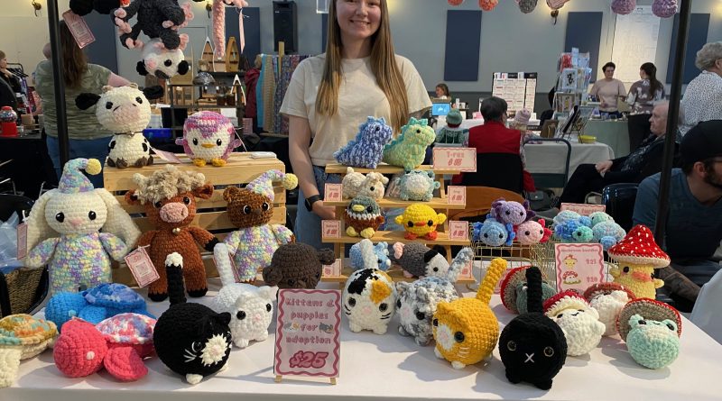A women poses with crocheted items.