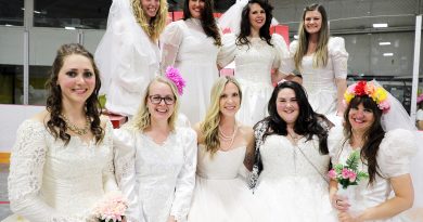 A group of women in wedding dresses pose for a photo.