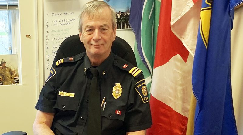A fire chief sits in a chair.