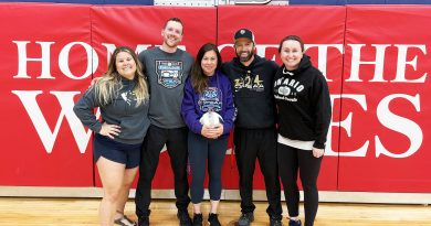 Four people pose for a photo in a gym.