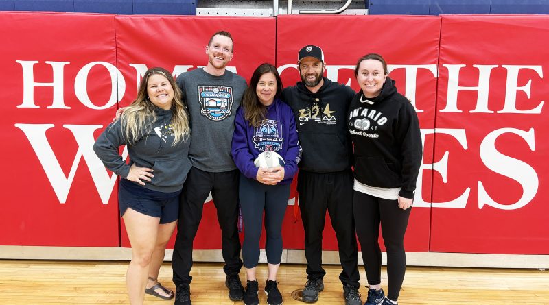 Four people pose for a photo in a gym.