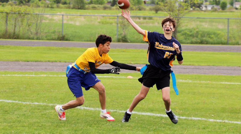 A person throws a football while being chased.