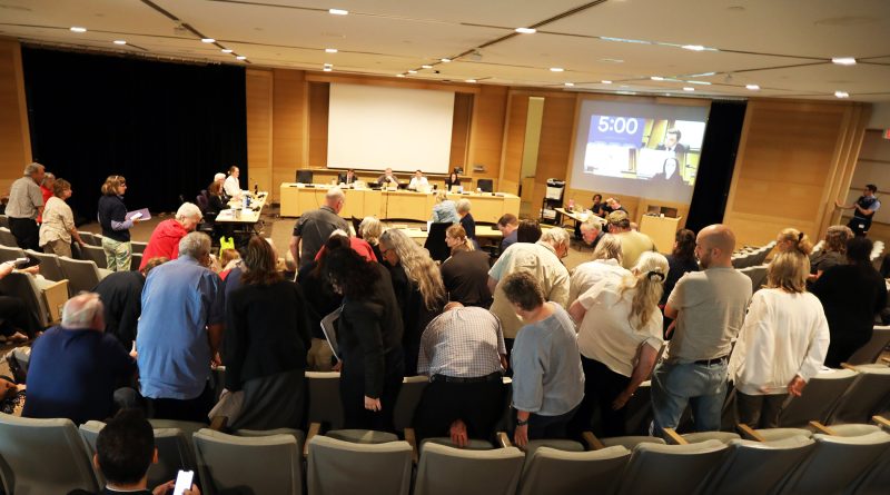 A group of people stand in an auditorium.