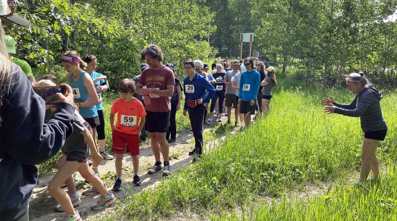 A group of runners move through the forest.
