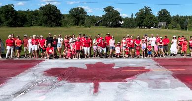 A photo of people posing in front of a Canada Flag.