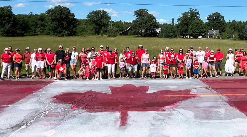 A photo of people posing in front of a Canada Flag.