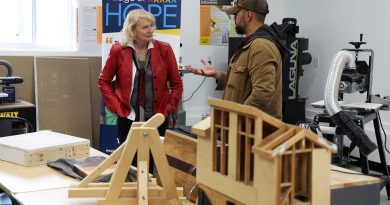 Two people talk in a woodworking room.