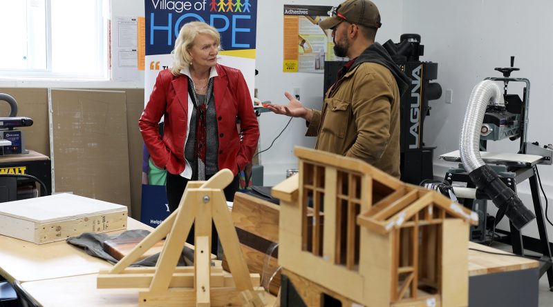 Two people talk in a woodworking room.