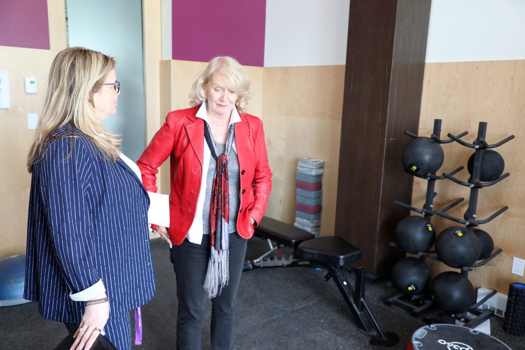 Two people talk in a workout room.