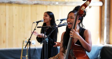 A woman sings and plays the bass.