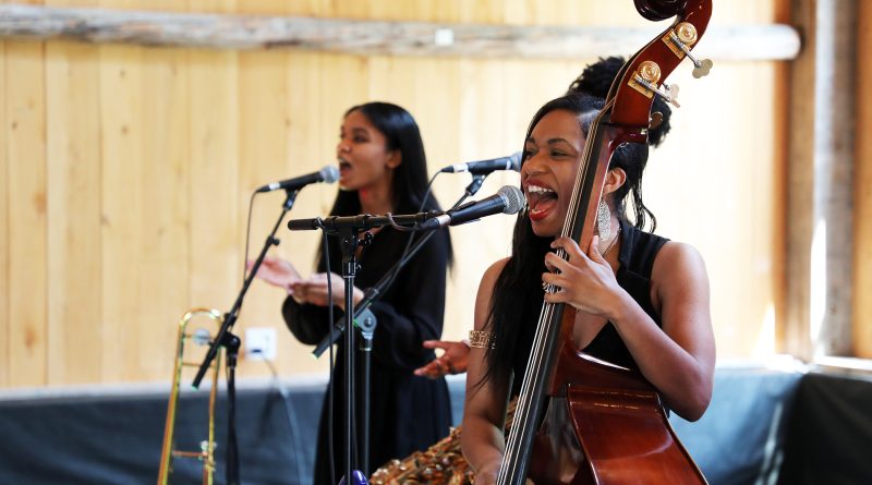 A woman sings and plays the bass.