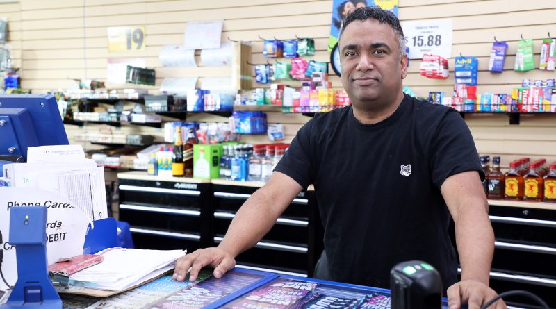 A man poses in his convenience store.