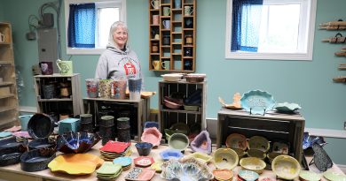 An artist poses behind her work.