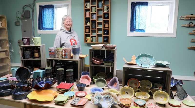 An artist poses behind her work.