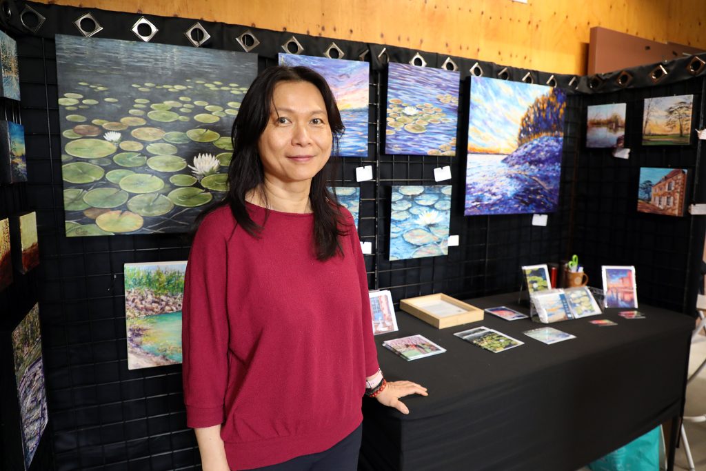 A woman poses in front of her art.