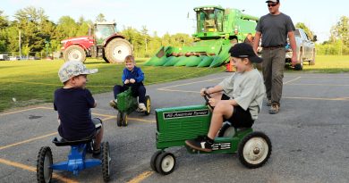 Boys ride around on mini-tractors.